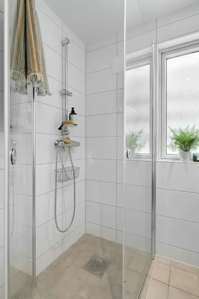 Douche italienne aux tons gris avec carrelage grand format, éclairage naturel par une fenêtre