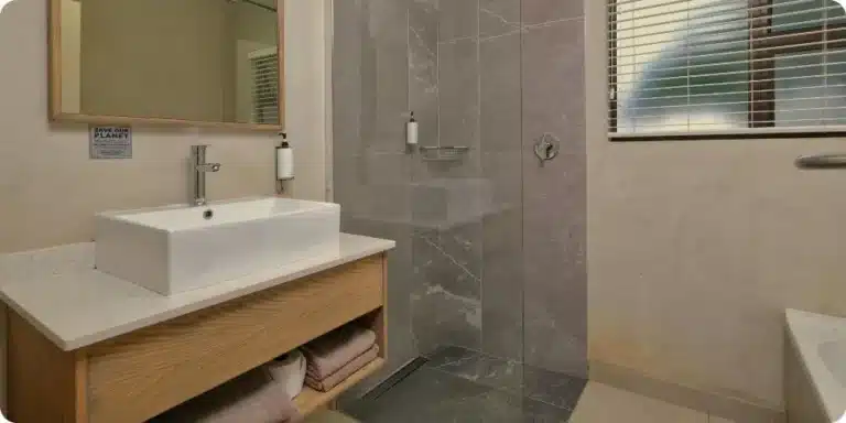 Douche italienne moderne avec paroi vitrée et carrelage grand format gris dans une salle de bain rénovée