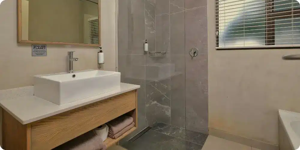 Douche italienne moderne avec paroi vitrée et carrelage grand format gris dans une salle de bain rénovée