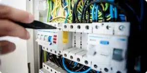 Électricien intervenant sur un tableau de disjoncteurs ouvert lors d'une rénovation électrique