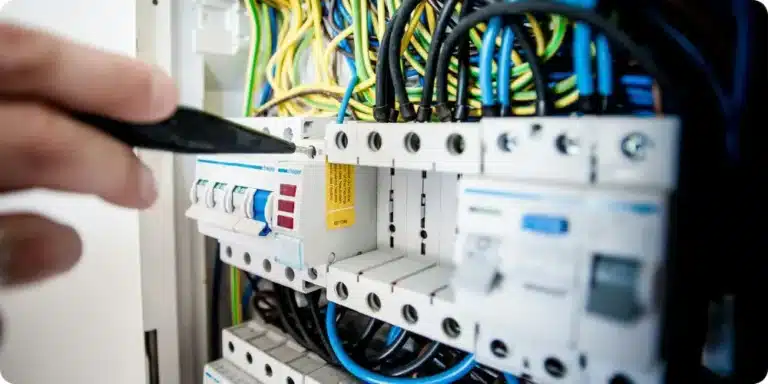 Électricien intervenant sur un tableau de disjoncteurs ouvert lors d'une rénovation électrique