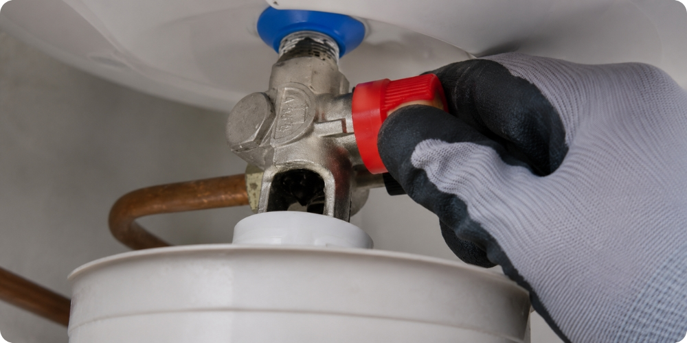 Ouverture du robinet de purge rouge sur un groupe de sécurité chauffe-eau