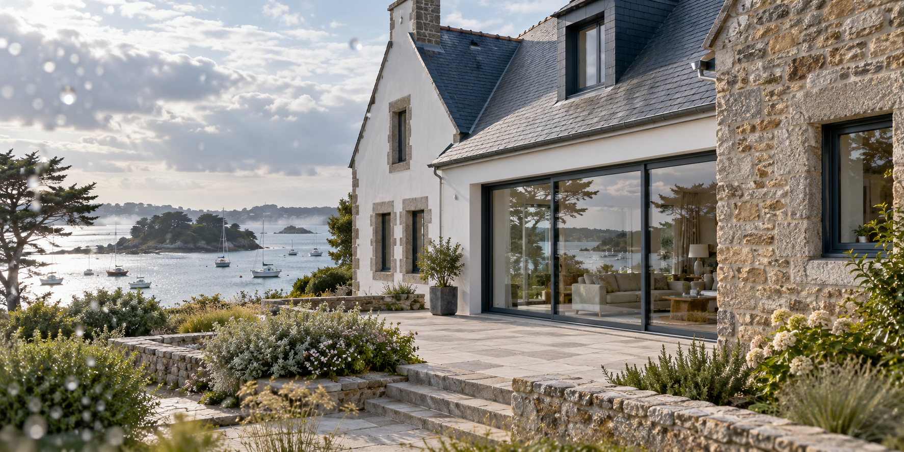 Maison bretonne aux fenêtres neuves en aluminium gris ardoise face au golfe du Morbihan, gouttes d’embruns sur la vitre
