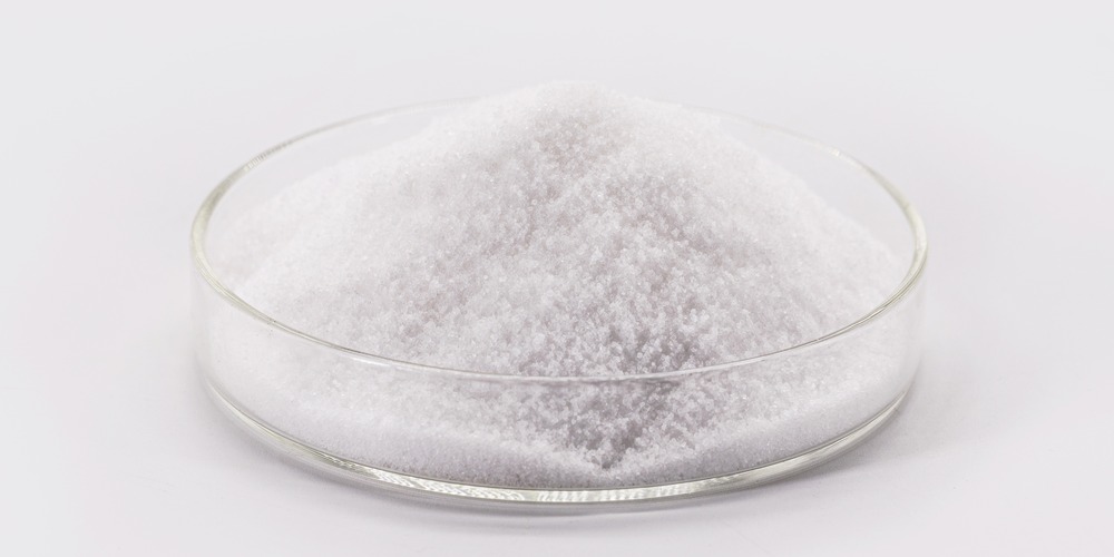 Acide citrique en poudre dans une coupelle en verre, un produit classé irritant pour les yeux et les voies respiratoires