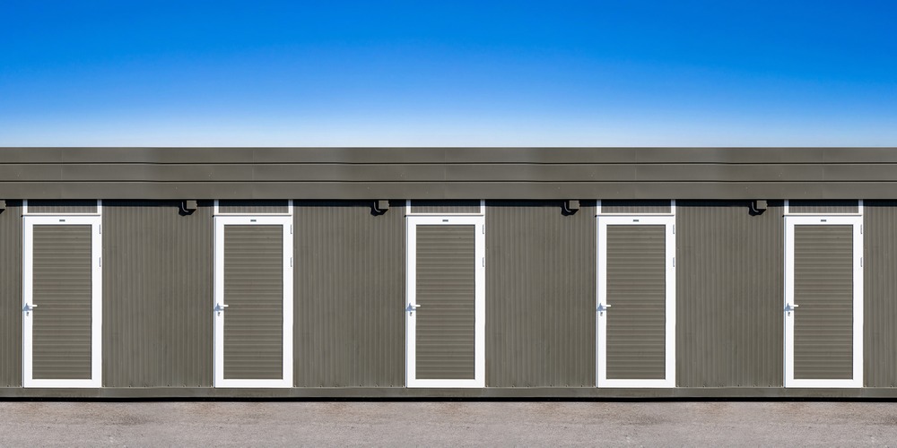 Rangée de modules préfabriqués d'une base vie de chantier, avec une porte d'accès par module
