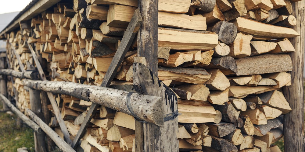 Bûches de bois sec fendues et rangées à l'abri, prêtes à brûler dans un insert de cheminée ancienne