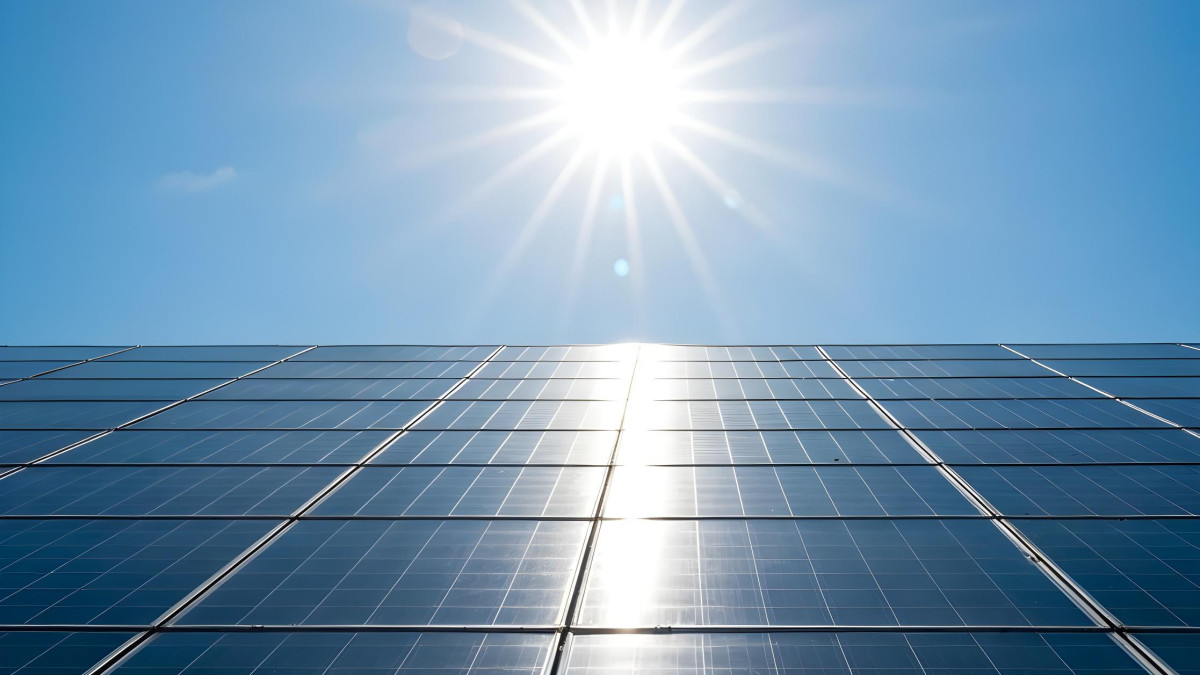 Des panneaux solaires sont placés sur la toiture d'une maison avec le soleil diffusant son énergie.